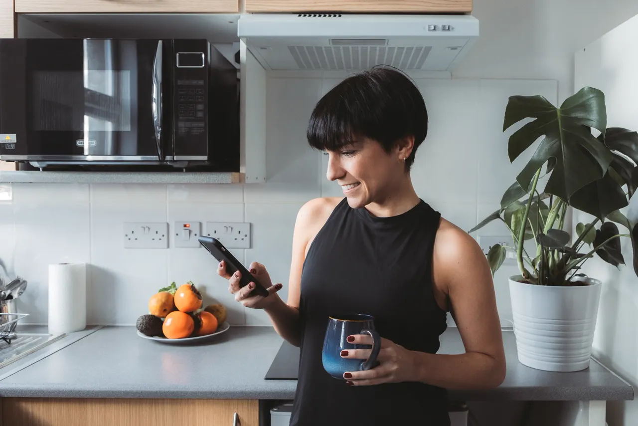 A woman in her kitchen looking at her phone