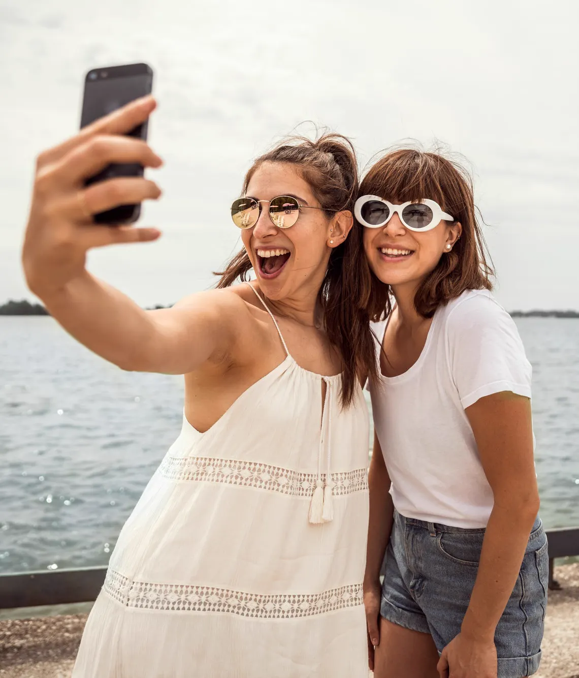 Two friends taking a selfie by the water